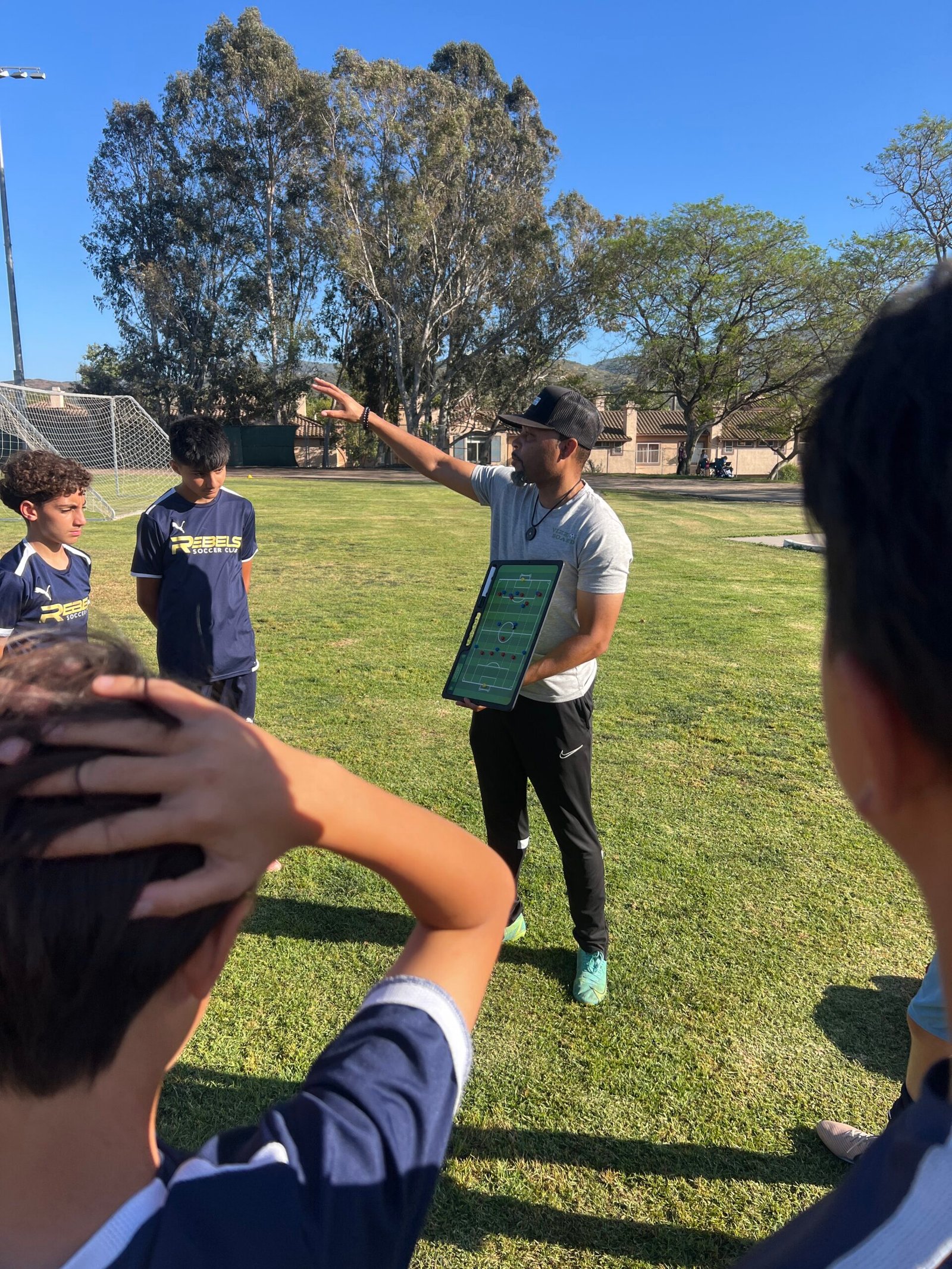 Soccer coach using Vizzionboard tactics board with players during training session
