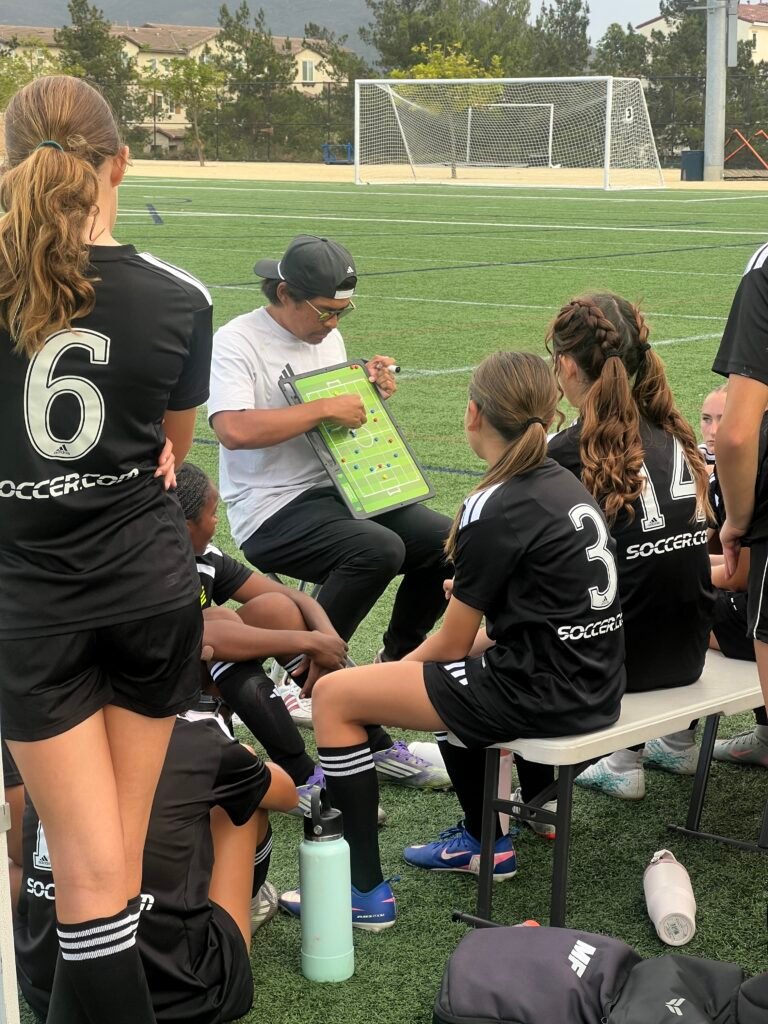 Youth soccer coach using a tactics board to walk his team through a play on the sideline
