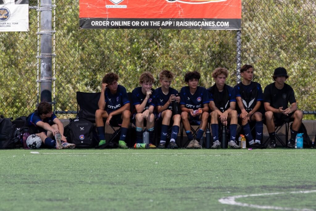 Young soccer players sitting on a bench during a game.