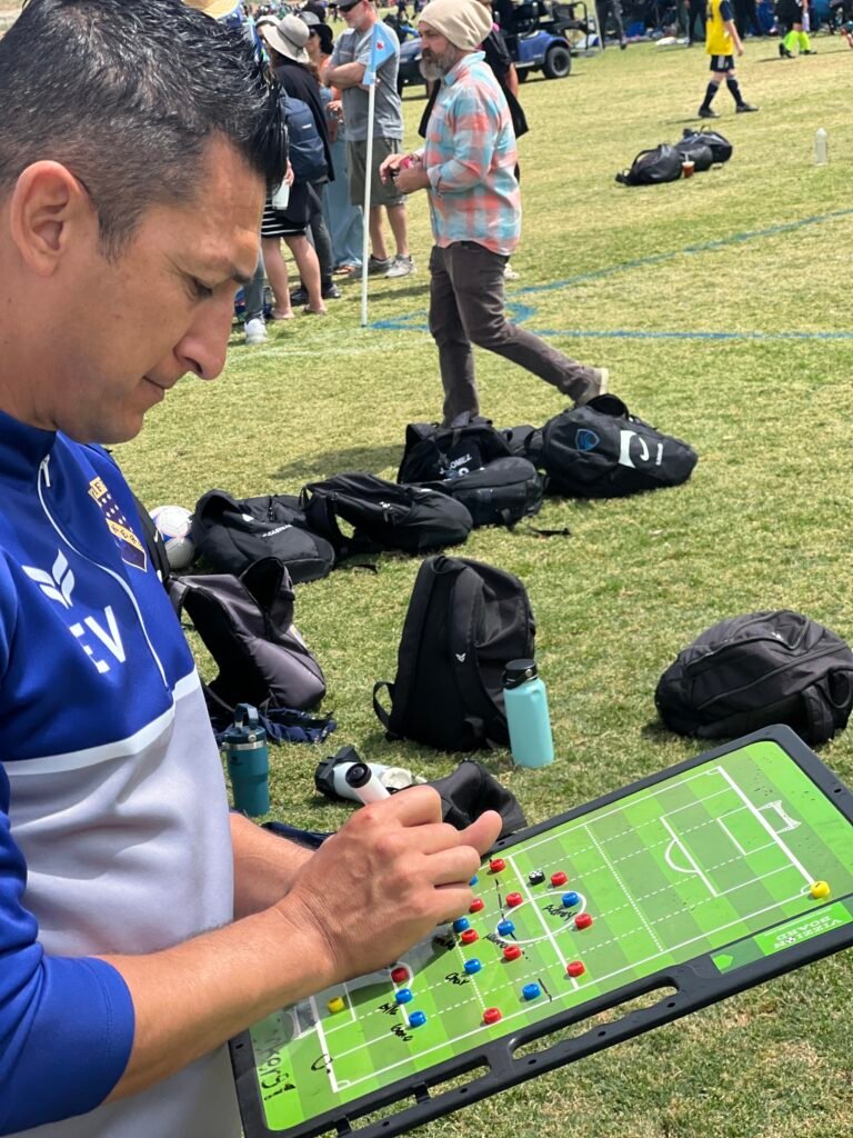 Coach using a Vizzionboard soccer tactics board on the sideline during a match