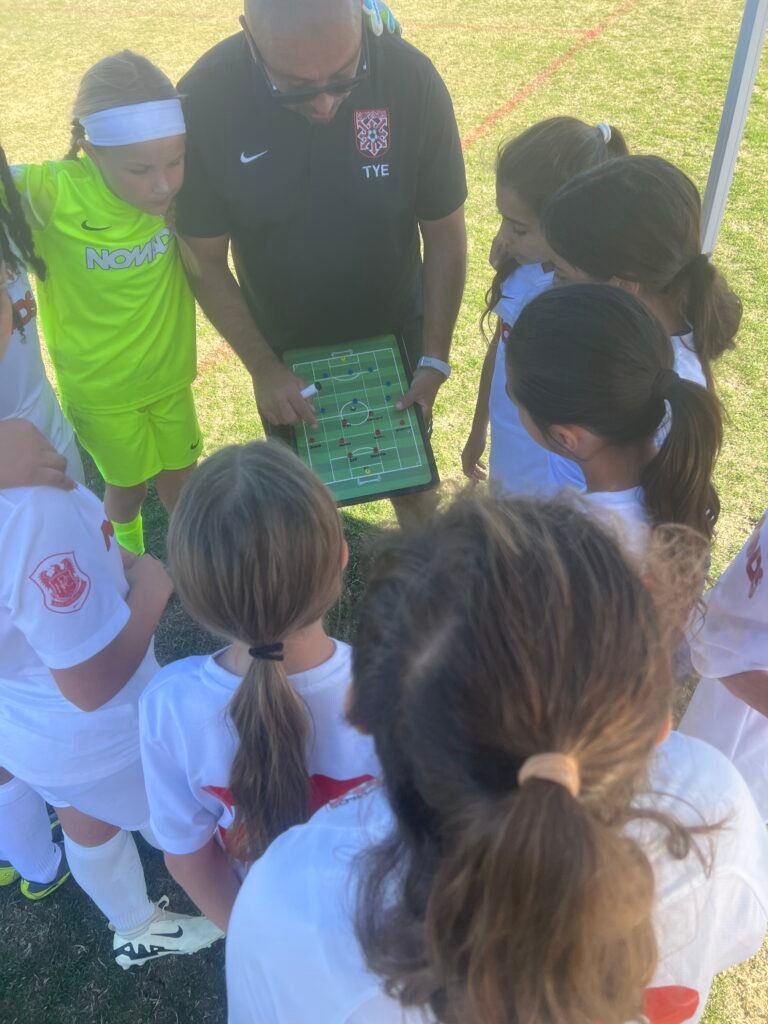 Youth soccer coach using a Vizzionboard tactics board with his team during a match huddle