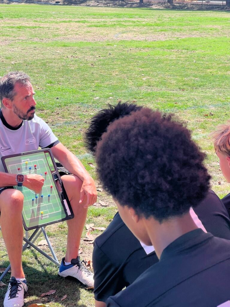 A coach using a Vizzionboard soccer tactics board to show a formation to a player on the sideline